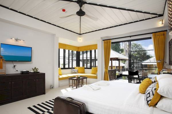 Schlafzimmer im Moracea by Khao Lak Resort mit Bett, Fernseher und Fenstern.