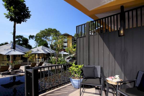 Aussicht von der Balkon des Moracea by Khao Lak Resorts mit Gartenmöbeln, Pflanzen und Swimmingpool.