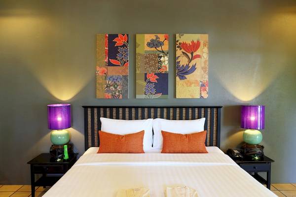 Hotelzimmer im Moracea by Khao Lak Resort mit Bett, Kissen, Lampen und drei Wandgemälden.