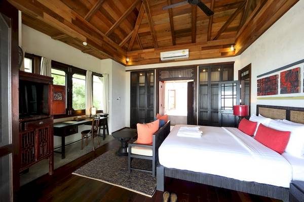 Schlafzimmer im Moracea by Khao Lak Resort mit Bett, Fenstern und Holzmöbeln.