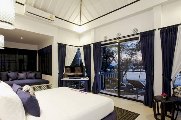 Schlafzimmer im Moracea by Khao Lak Resort mit großem Bett, Fernseher, und Ausblick auf den See.