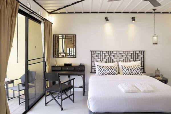 Innenansicht eines Zimmers im Moracea by Khao Lak Resort mit Bett, Schreibtisch und Blick auf den Balkon.