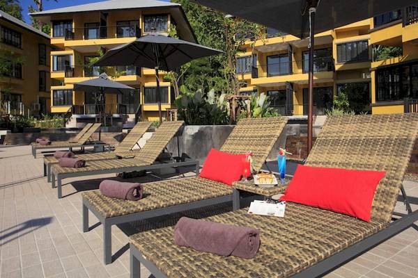 Außenbereich des Moracea by Khao Lak Resorts mit mehreren Liegestühlen und Sonnenschirmen.