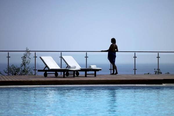 Person am Pool-Geländer des Esperos Village Blue & Spa
