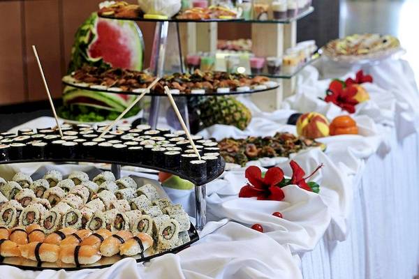 Ein Buffet-Tisch mit verschiedenen Sushi-Rollen und frischen Früchten.