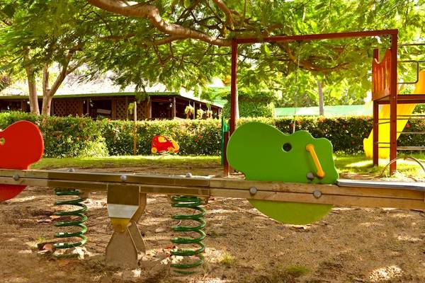 Kinderspielplatz im Garten des Iberostar Tainos Hotels mit bunten Spielgeräten und Bäumen.