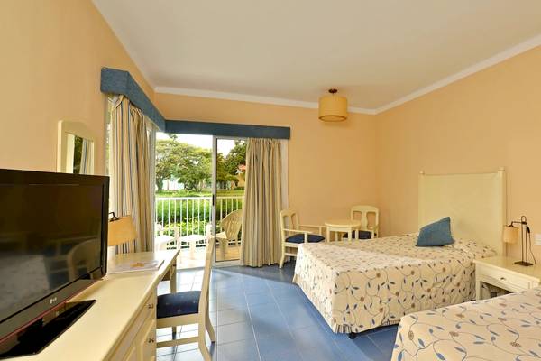 Doppelzimmer im Iberostar Tainos Hotel mit zwei Betten, Fernseher, Schreibtisch und Balkon.
