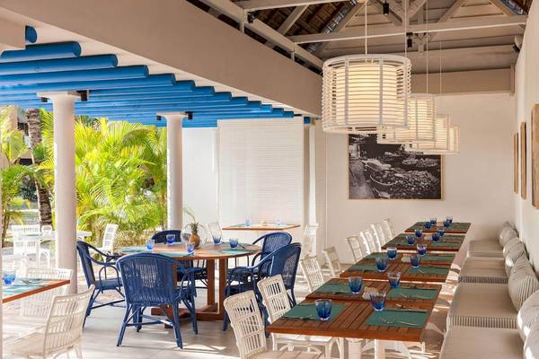 Innenansicht des Restaurants des Veranda Pointe Aux Biches Hotels mit blauen Stühlen und Tischen.