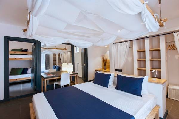 Schlafzimmer im Veranda Pointe Aux Biches Hotel mit Bett, Schreibtisch und Hängelampen.