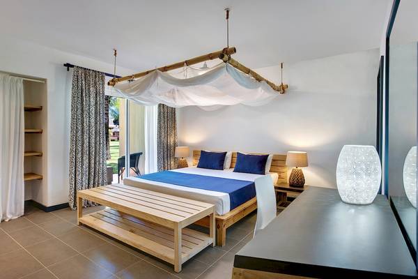 Schlafzimmer im Veranda Pointe Aux Biches Hotel mit Bett, Moskitonetz, Nachttischen und Lampen.