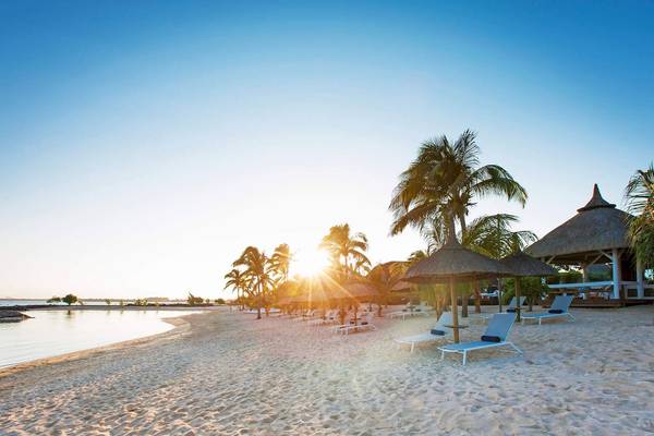 Strand des Veranda Pointe Aux Biches Hotels mit Sonnenuntergang und Lounge-Stühlen