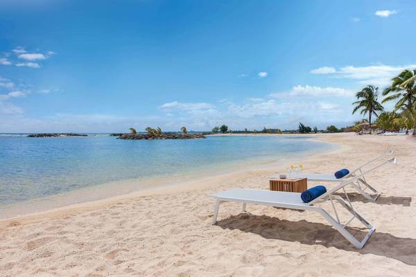 Strandlounge am Veranda Pointe Aux Biches Hotel mit weißen Sonnenliegen und einem Tisch