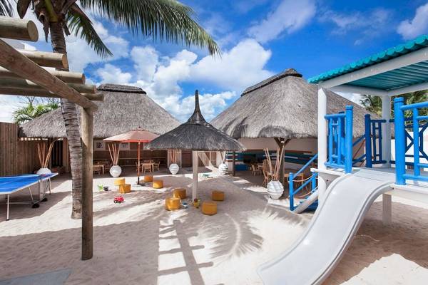 Kinderspielplatz im Veranda Pointe Aux Biches Hotel mit Rutsche, Spielgeräten und Strohhütten.