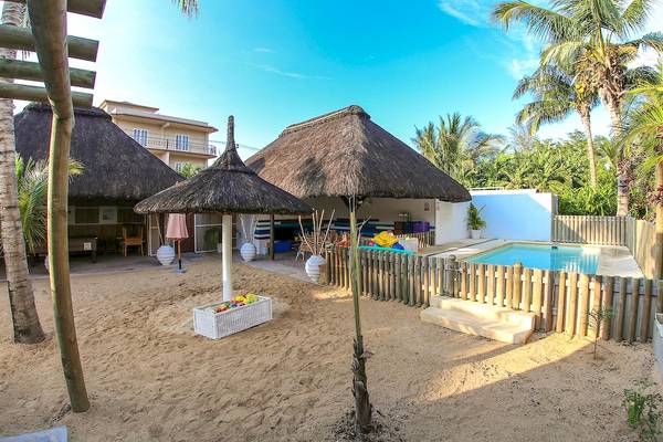 Außenbereich des Veranda Pointe Aux Biches Hotels mit Pool, Sonnenschirmen und bepflanzten Bereichen.