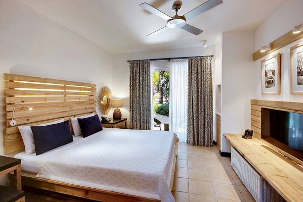 Ein elegantes Schlafzimmer im Veranda Pointe Aux Biches Hotel mit einem großen Bett und modernen Möbeln.