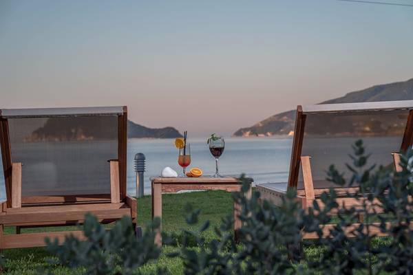 Zwei Holzstühle am Strand mit Getränken und Blick auf das Meer