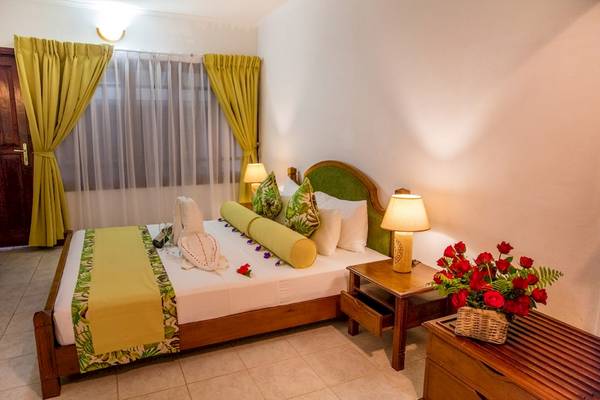 Schlafzimmer im La Digue Island Lodge mit Bett, Tisch, Blumen und Lampen