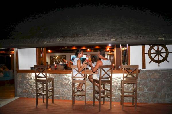 Zwei Gäste sitzen bei Nacht an der Bar des La Digue Island Lodge.