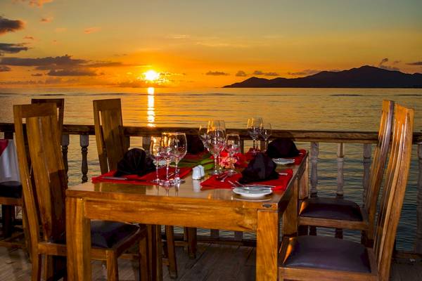 Tisch auf einer Terrasse mit Sonnenuntergang im Hintergrund am Meer