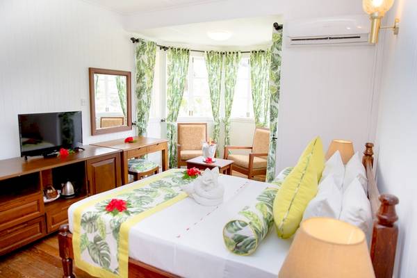Innenansicht eines Zimmers im La Digue Island Lodge mit Bett, Fernseher und Möbeln.