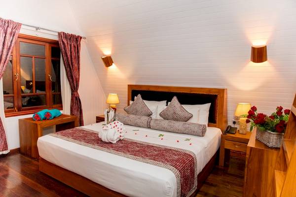 Schlafzimmer im La Digue Island Lodge mit weißem Bett und roten Dekorelementen.