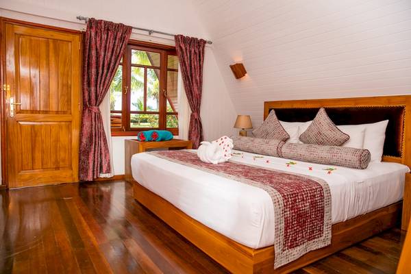 Schlafzimmer im La Digue Island Lodge mit Bett, Kissen, Lampe und Fenstern