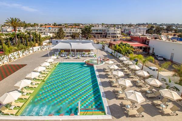 Luftaufnahme des Nicholas Color Hotels mit Swimmingpool, Sonnenliegen und Sonnenschirmen.