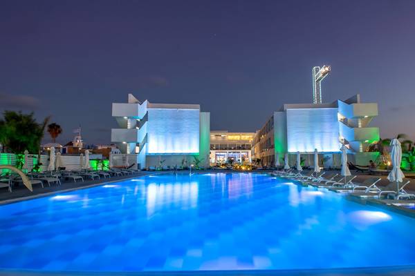 Der Pool des Nicholas Color Hotels bei Nacht, beleuchtet und mit Sonnenliegen umgeben.