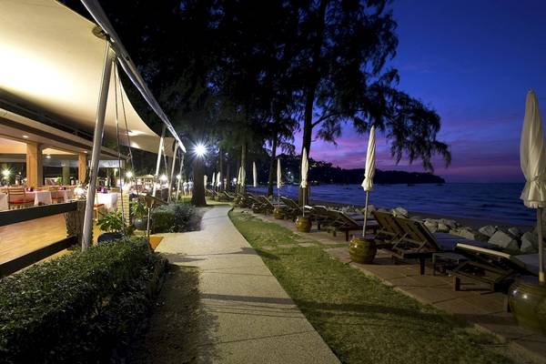 Abendlicher Blick auf den Strand des Best Western Premier Bangtao Beach Resort mit Lounge-Stühlen, Schirmen und einem Gehweg.