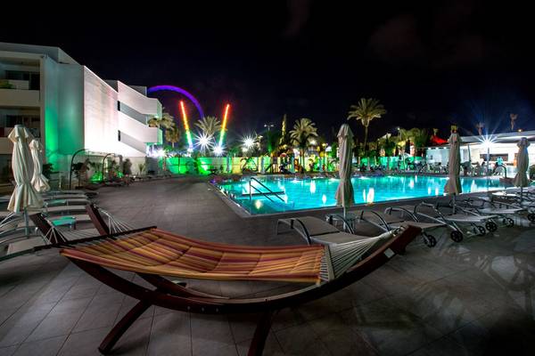 Poolbereich des Nicholas Color Hotels bei Nacht mit bunten Lichtern und Liegestühlen