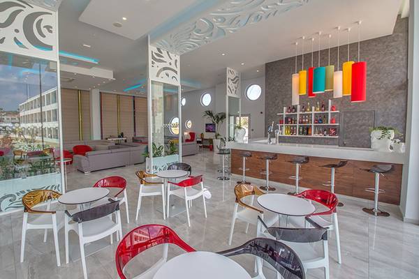 Innenbereich des Nicholas Color Hotel mit bunten Stühlen, Tischen und einer Bar.