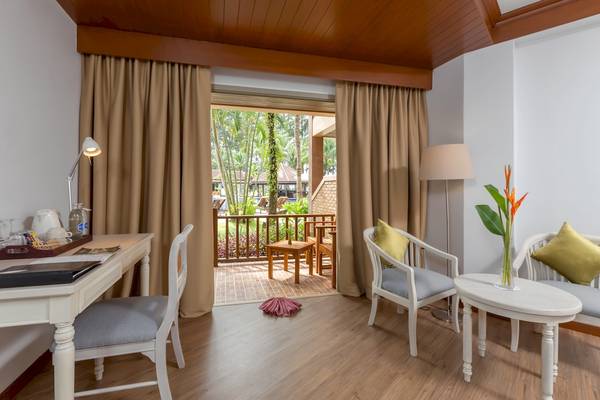 Innenansicht eines Zimmers im Best Western Premier Bangtao Beach Resort mit Schreibtisch, Stühlen und einem Balkon.