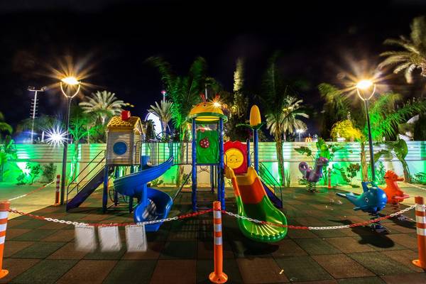 Nachtansicht des Kinderspielplatzes im Nicholas Color Hotel mit bunten Spielgeräten und Beleuchtung.