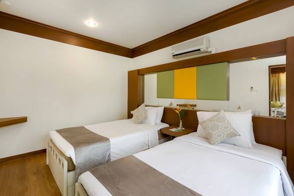 Schlafzimmer im Best Western Premier Bangtao Beach Resort mit zwei Betten, Nachttischen und einer Klimaanlage.