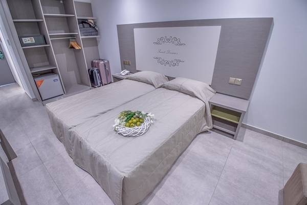 Doppelbett-Zimmer im Nicholas Color Hotel mit Obstkorb auf der Bettdecke.