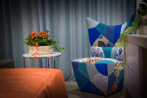 Zimmer im Nicolas Color Hotel mit einem gemusterten Stuhl und einem Tisch mit Blumen.