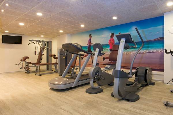 Fitnesscenter im Iberostar Selection Albufera Playa Hotel mit Trainingsgeräten und einer Wand mit Strandmotiv.