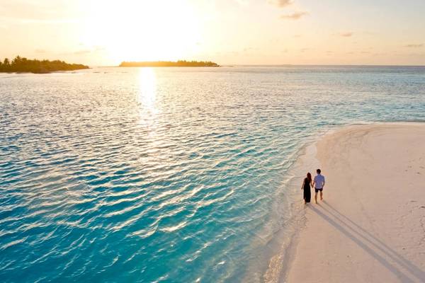 Paar am Strand der Villa Park, Malediven, bei Sonnenuntergang