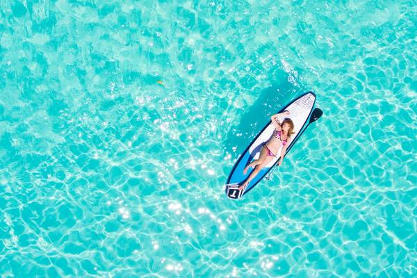 Frau im Bikini auf einem Surfbrett im Wasser, Villa Park, Maldives
