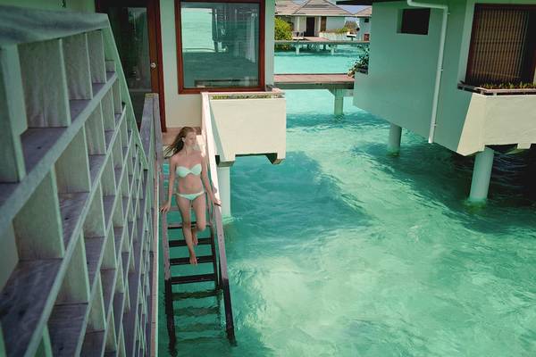 Frau in Bademode steigt auf Treppe ins Wasser bei Villa Park, Maldives