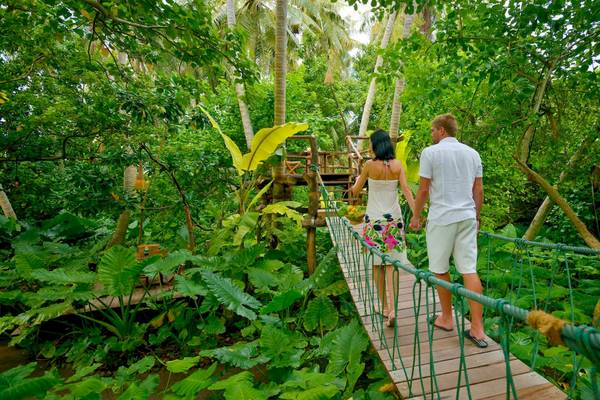 Paar auf einer Holzbrücke im tropischen Dschungel der Villa Park, Malediven.