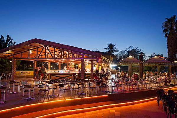 Außenbar des Belconti Resorts bei Nacht mit beleuchteten Tischen und Stühlen.
