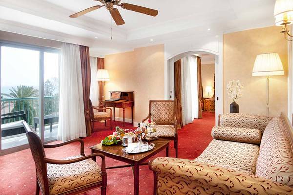Ein elegantes Hotelzimmer mit einem Sofa, einem Tisch, einem Schreibtisch und einem Balkon mit Aussicht.