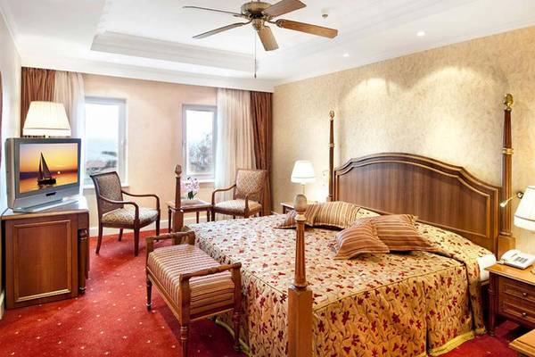Ein elegantes Schlafzimmer im Belconti Resort Hotel mit Doppelbett, Fernseher und Dekor.