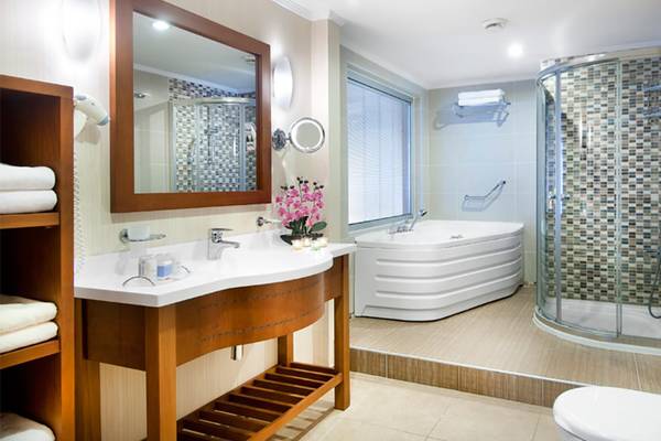 Badezimmer im Belconti Resort mit Badewanne, Dusche, Spiegel und Waschbecken.