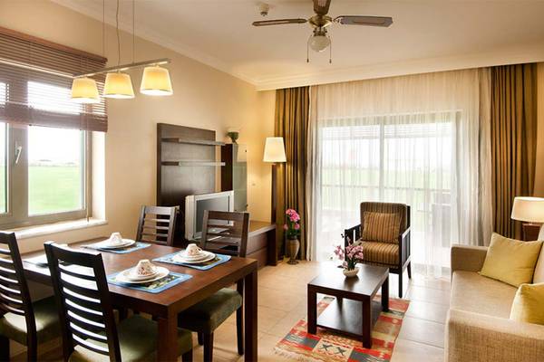 Wohnbereich des Belconti Resorts mit Esstisch, Sofa und Fenstern.
