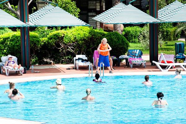 Mehrere Frauen schwimmen im Pool des Belconti Resorts, während eine Frau an der Seite steht.