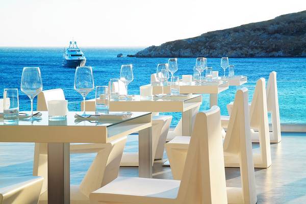 Terrasse des Petasos Beach Resort & Spa mit Blick auf das Meer und ein Boot