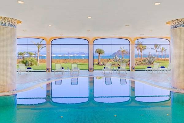 Poolbereich im Secrets Bahia Real Resort & Spa mit Blick auf das Meer und Palmen