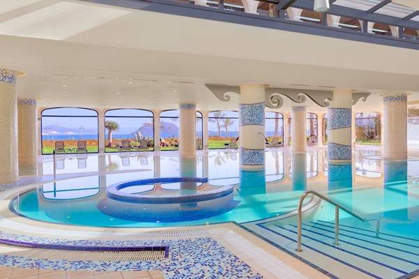 Ein großer Swimmingpool im Secrets Bahia Real Resort & Spa mit blauen Fliesen und Blick auf das Meer.